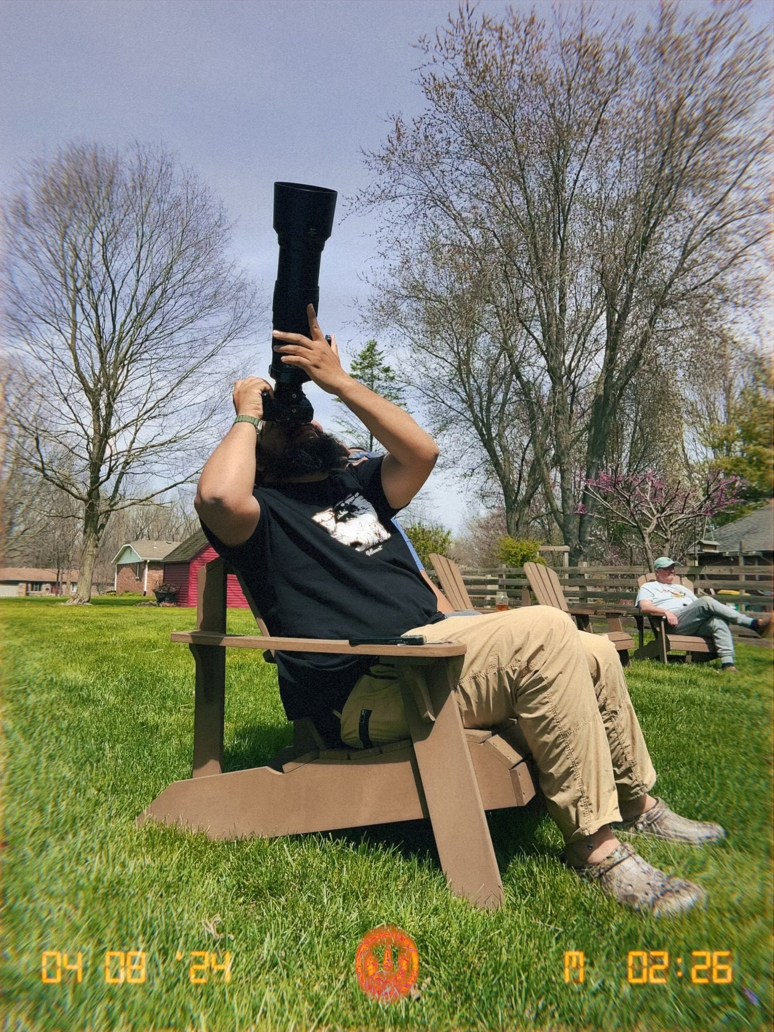 A photographer taking a picture of the solar eclipse pointing a camera directly up