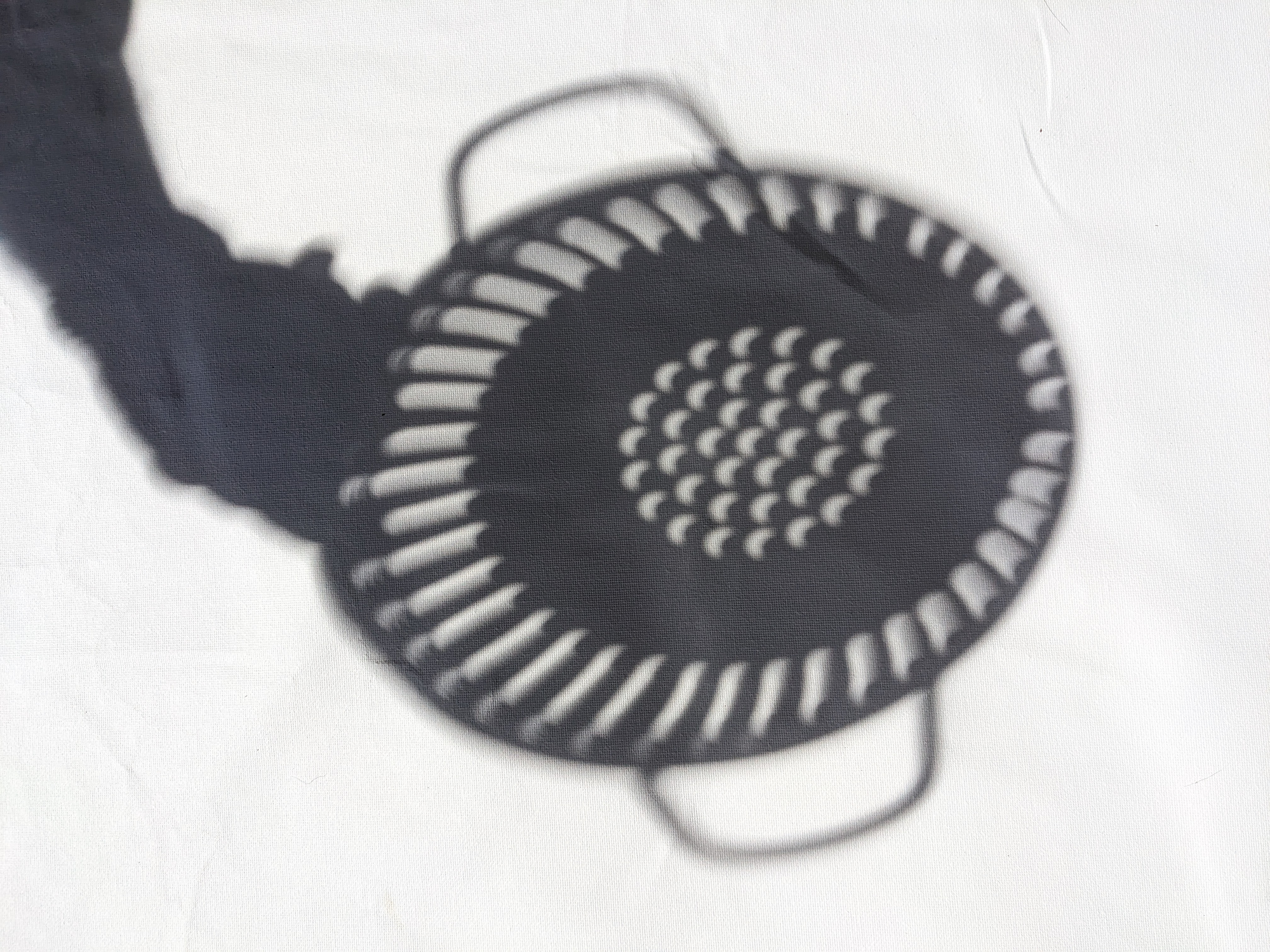 The solar eclipse seen in the shadow made by a colander.