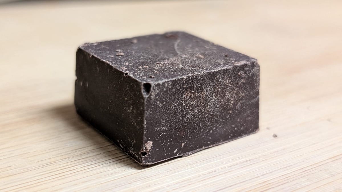A small block of chocolate on a wooden cutting board