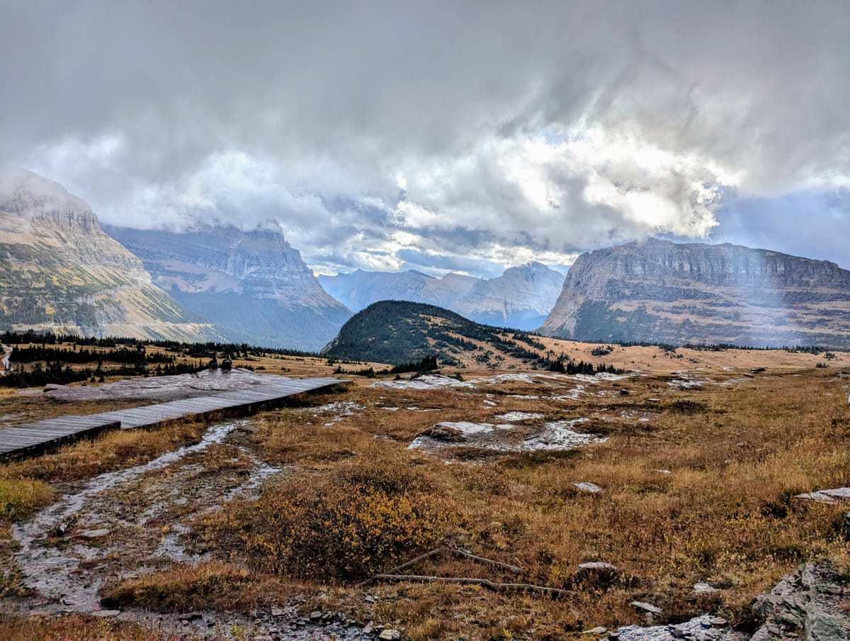 A view of mountains, meadows and a boardwalk in Glacier National Park.