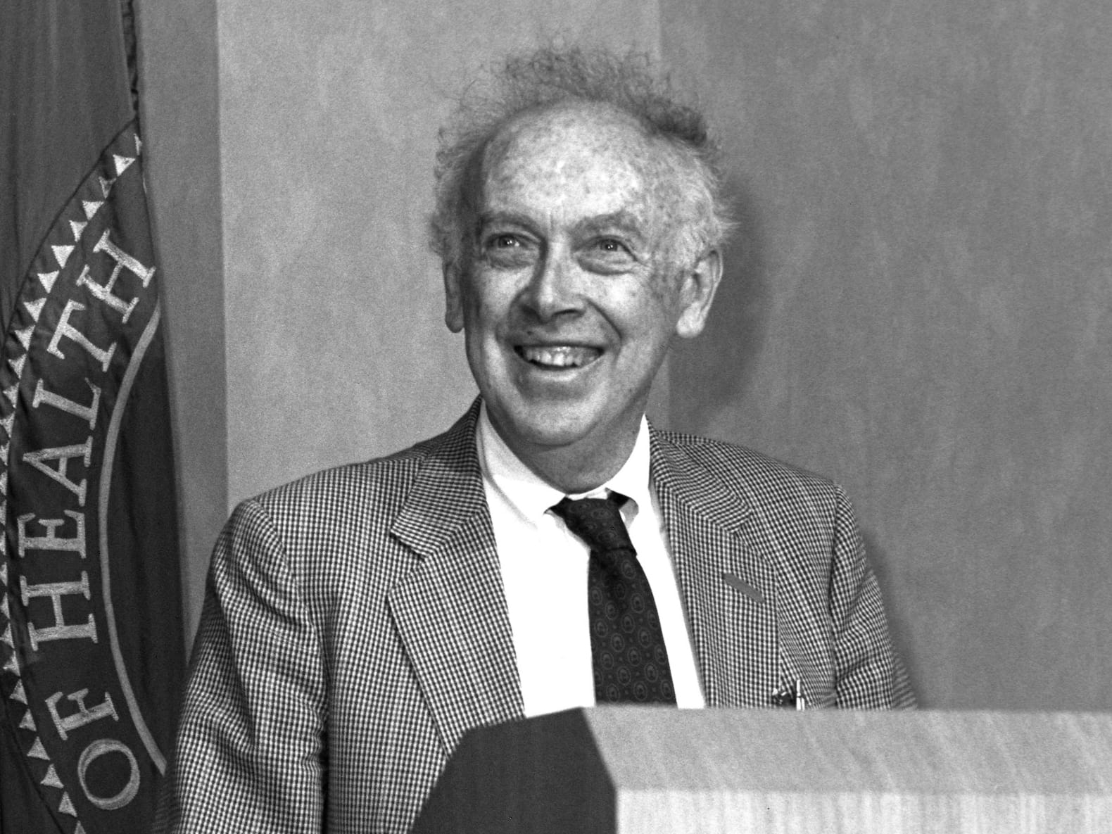 Biochemist James Watson standing at a lectern