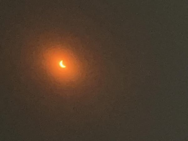 The sun colored red-orange, partially eclipsed.